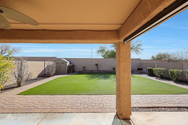 view of yard featuring a patio, ceiling fan, and a storage unit