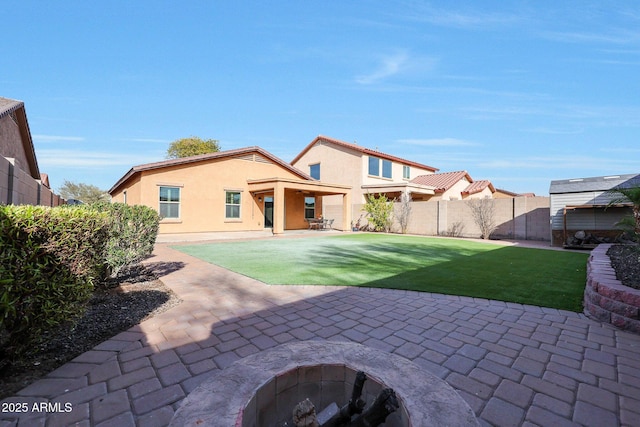 back of property featuring a fire pit, a patio area, and a lawn