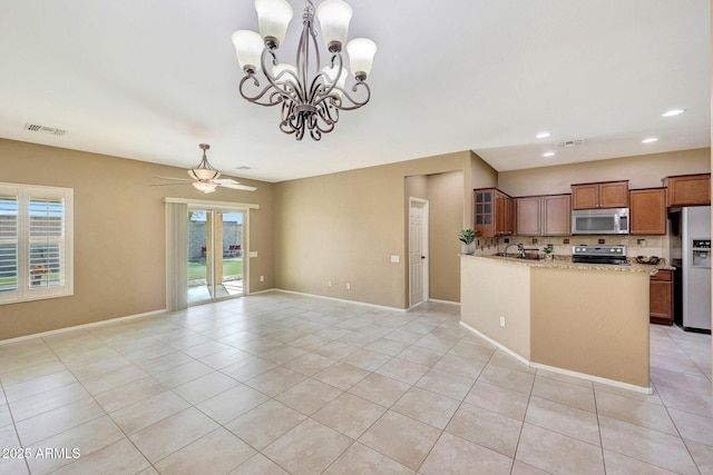 kitchen with decorative light fixtures, light tile patterned floors, kitchen peninsula, stainless steel appliances, and light stone countertops