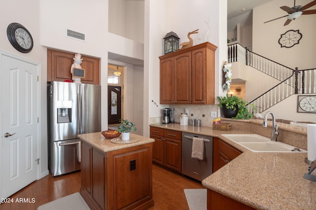 kitchen with sink, appliances with stainless steel finishes, a center island, a high ceiling, and kitchen peninsula