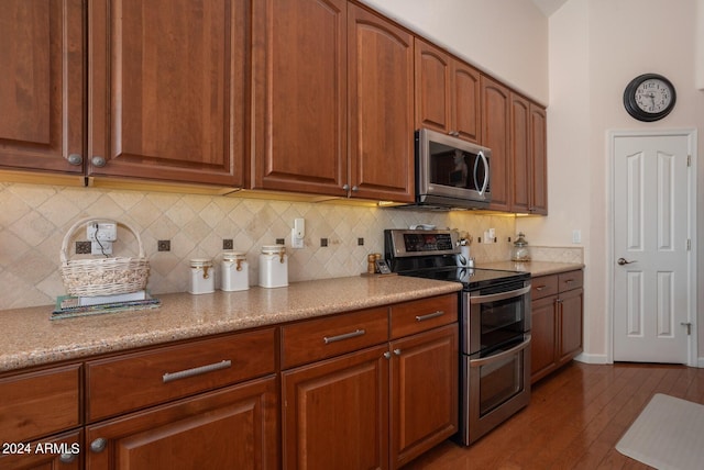 kitchen with appliances with stainless steel finishes, wood-type flooring, and backsplash