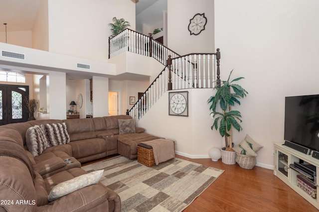 living room with a towering ceiling, hardwood / wood-style floors, and french doors