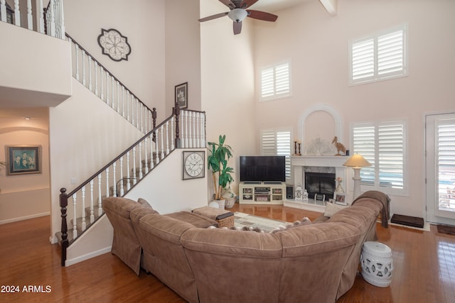 living room featuring wood-type flooring, a fireplace, and a high ceiling