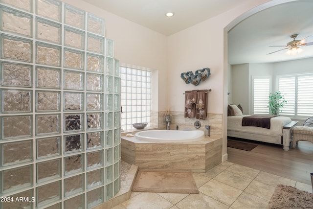 bathroom with tile patterned flooring, a relaxing tiled tub, and ceiling fan