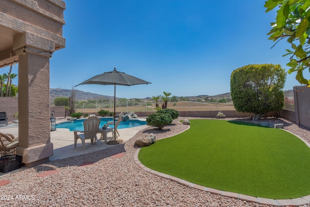 view of yard featuring a fenced in pool, a mountain view, and a patio