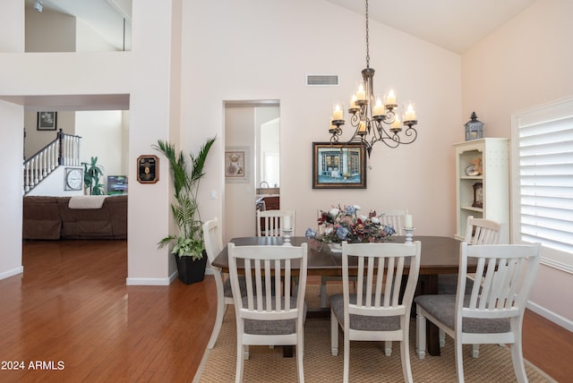 dining room with dark hardwood / wood-style flooring, high vaulted ceiling, and a notable chandelier