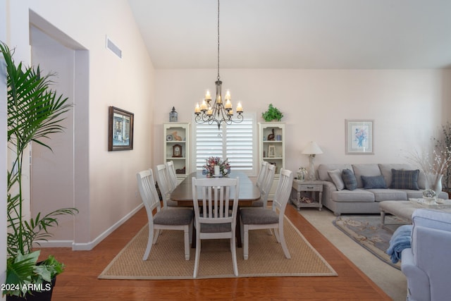 dining room featuring an inviting chandelier, hardwood / wood-style floors, and lofted ceiling