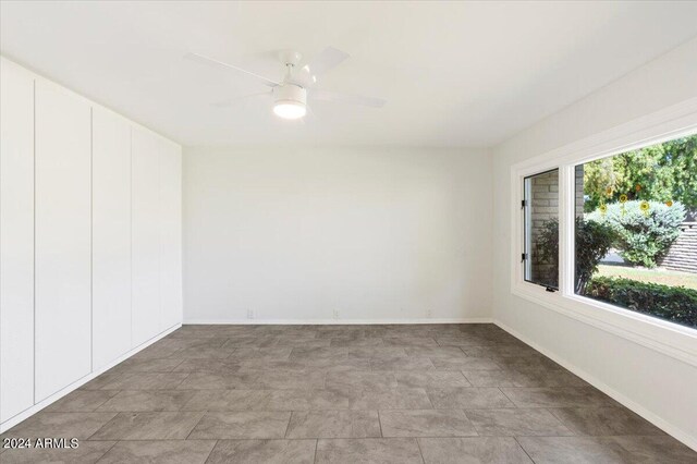 tiled spare room featuring ceiling fan