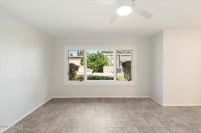 empty room with ceiling fan and light tile patterned floors