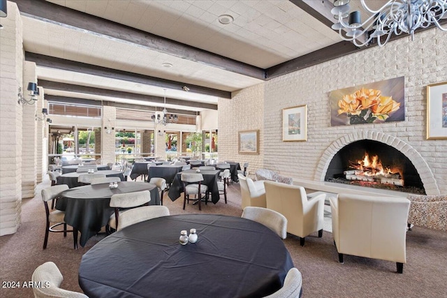 carpeted living room with a wealth of natural light, beam ceiling, a fireplace, and brick wall