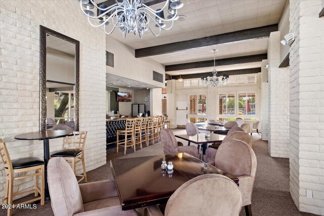 carpeted dining room with brick wall, an inviting chandelier, a high ceiling, and beam ceiling