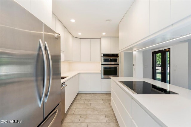 kitchen featuring stainless steel appliances, light tile patterned floors, and white cabinetry