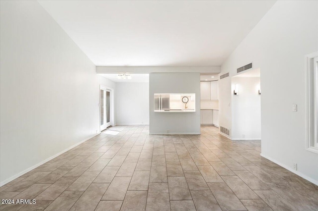 unfurnished living room with lofted ceiling and light tile patterned floors