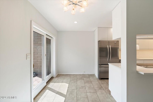 kitchen with a notable chandelier, light countertops, freestanding refrigerator, white cabinets, and baseboards