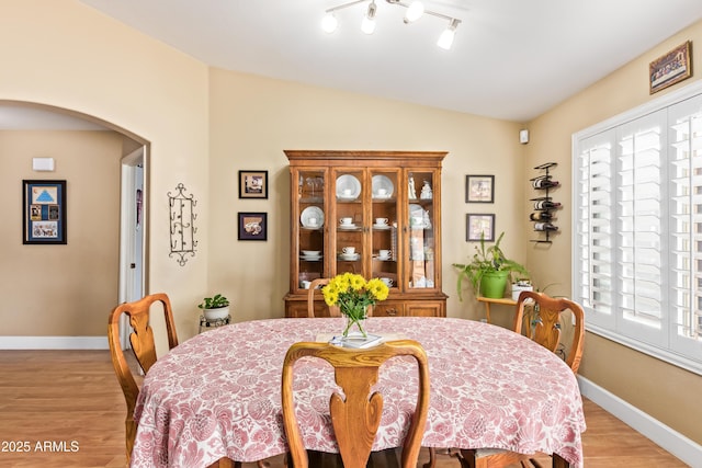 dining space featuring vaulted ceiling and light hardwood / wood-style flooring