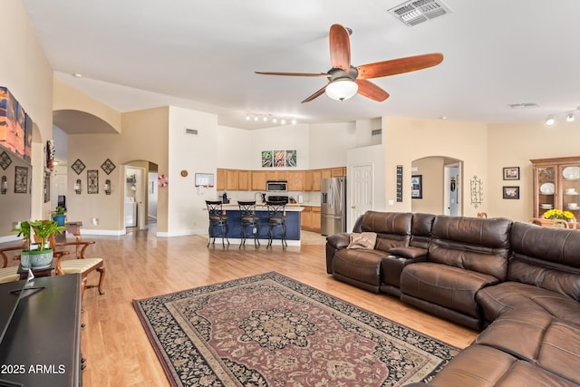 living room featuring ceiling fan, light hardwood / wood-style flooring, washer / clothes dryer, and high vaulted ceiling