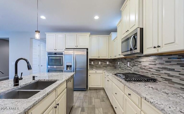 kitchen with a sink, hanging light fixtures, decorative backsplash, and appliances with stainless steel finishes