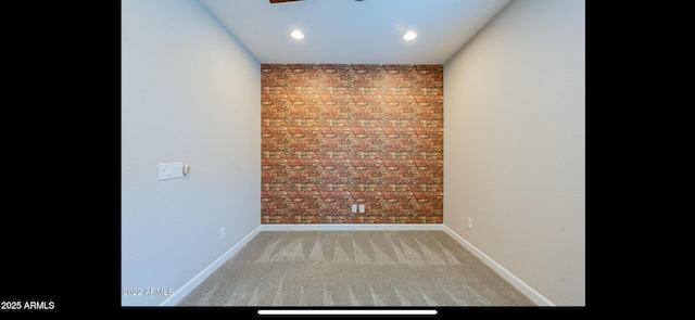 empty room featuring carpet floors, ceiling fan, brick wall, and baseboards