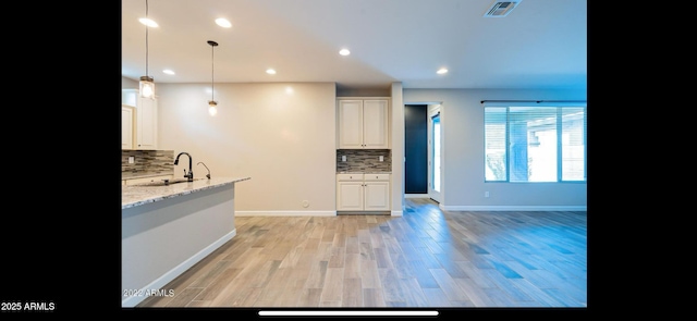 kitchen with light stone countertops, tasteful backsplash, visible vents, recessed lighting, and a sink