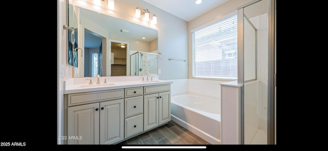bathroom featuring a shower stall, double vanity, a bath, and a sink