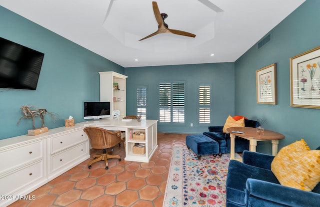 office space with a tray ceiling and ceiling fan