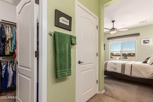 carpeted bedroom featuring tile patterned floors, a ceiling fan, and visible vents