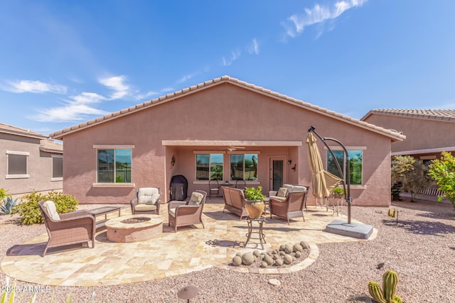 rear view of house with a patio area, stucco siding, an outdoor living space with a fire pit, and a ceiling fan