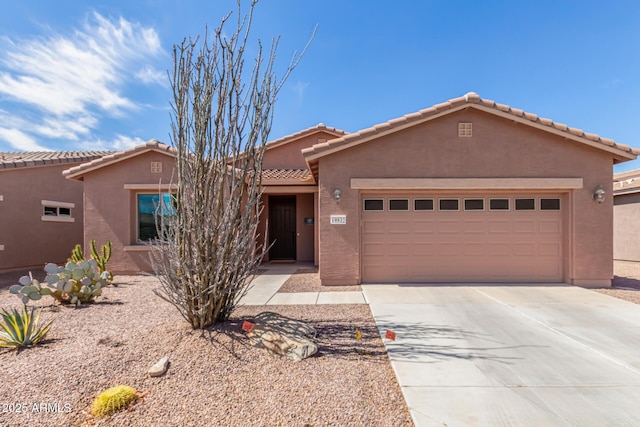 view of front of property featuring stucco siding, driveway, a tile roof, and a garage