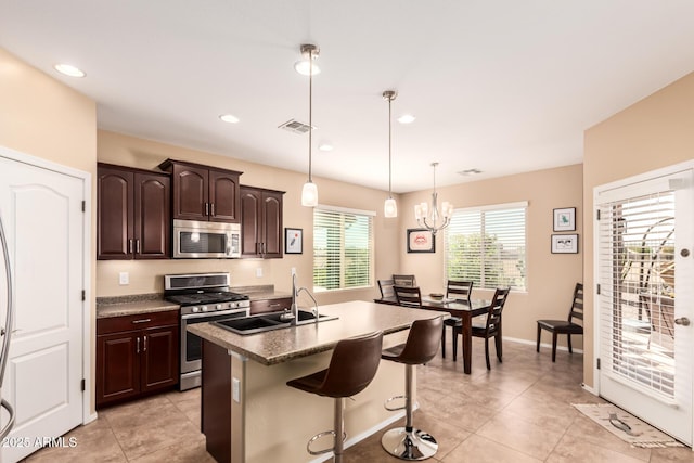 kitchen with visible vents, a breakfast bar, a sink, stainless steel appliances, and hanging light fixtures