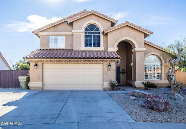 mediterranean / spanish-style house featuring an attached garage, driveway, fence, and stucco siding