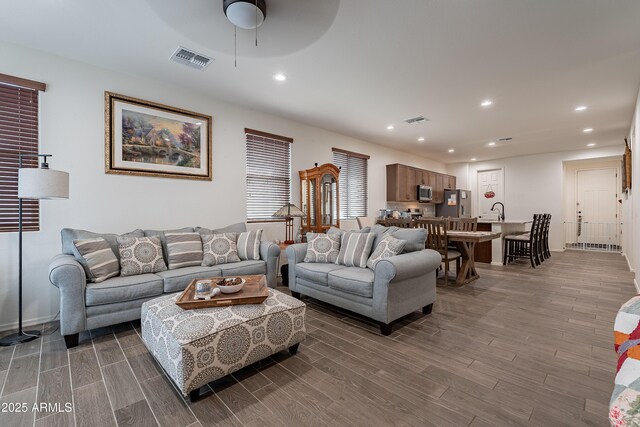 kitchen featuring light wood-type flooring, backsplash, an island with sink, sink, and stainless steel appliances