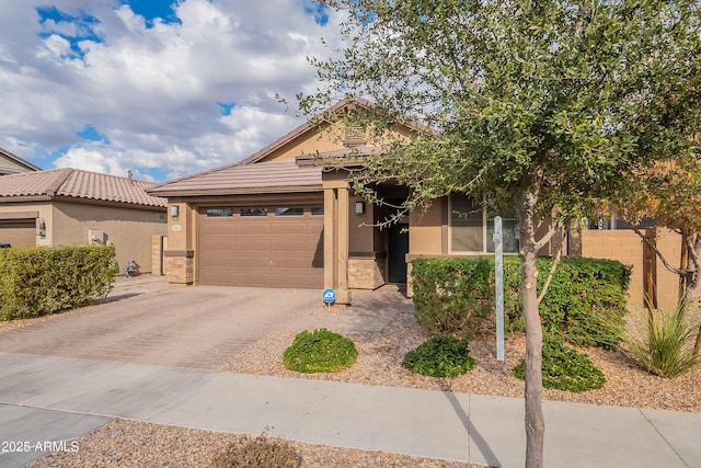 view of front of property with a garage, stone siding, fence, decorative driveway, and stucco siding