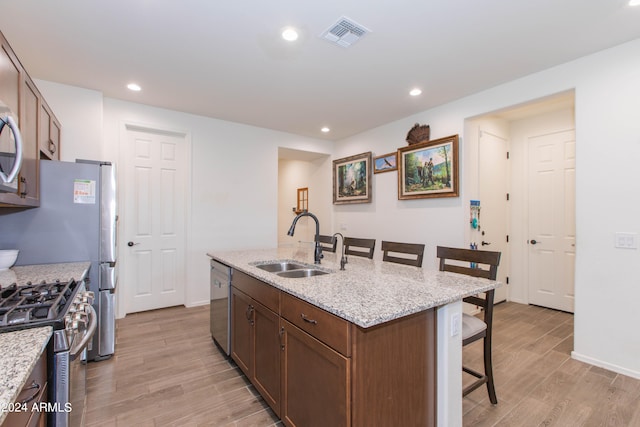 kitchen with sink, light wood-type flooring, gas range, and a kitchen island with sink