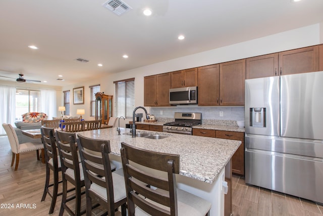 kitchen featuring appliances with stainless steel finishes, a sink, visible vents, and tasteful backsplash