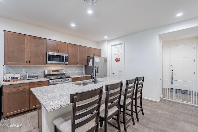 kitchen with a breakfast bar, appliances with stainless steel finishes, backsplash, and a sink