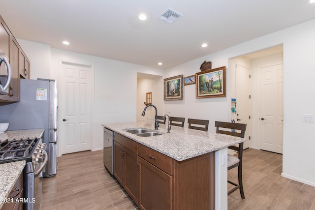 kitchen featuring a sink, visible vents, a kitchen breakfast bar, appliances with stainless steel finishes, and a center island with sink