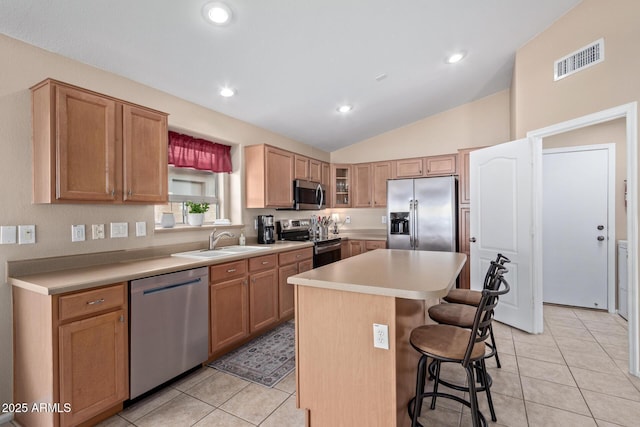 kitchen featuring sink, a center island, light tile patterned floors, appliances with stainless steel finishes, and a kitchen breakfast bar