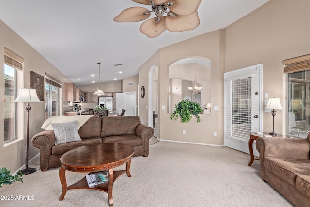 living room with vaulted ceiling, ceiling fan with notable chandelier, and light carpet