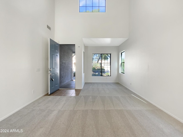 carpeted entrance foyer with a towering ceiling