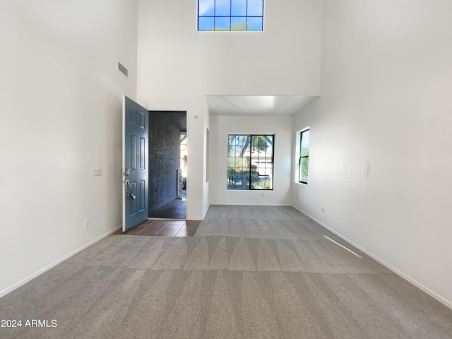 carpeted entryway with a towering ceiling