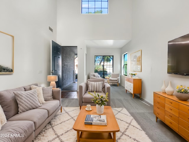 carpeted living room featuring a towering ceiling