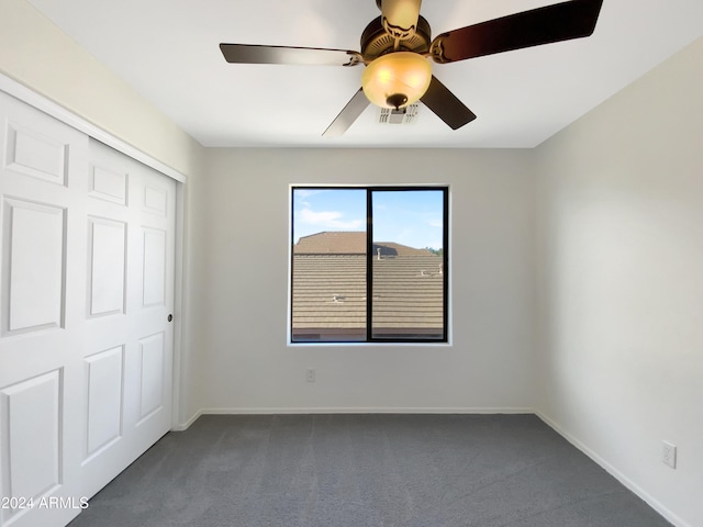 unfurnished bedroom featuring ceiling fan, a closet, and dark colored carpet