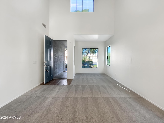 unfurnished living room featuring a high ceiling and dark carpet