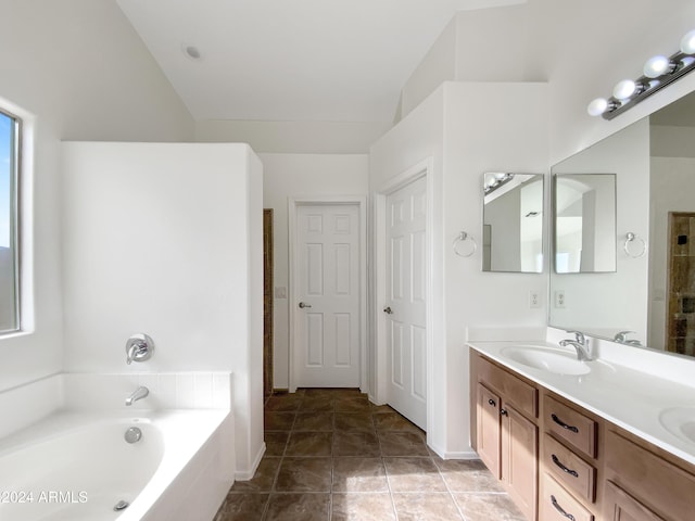 bathroom with tile patterned flooring, vanity, and tiled tub