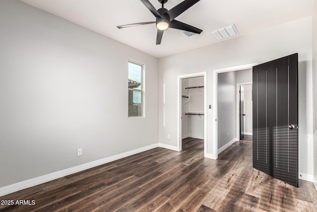 21972 N 97th Gln, Peoria, AZ 85383 - unfurnished bedroom with a walk in closet, visible vents, wood finished floors, baseboards, and a closet