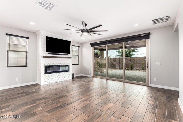 21972 N 97th Gln, Peoria, AZ 85383 - unfurnished living room featuring visible vents, a ceiling fan, wood finished floors, and a fireplace