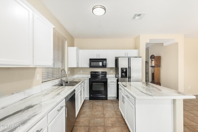 kitchen with light stone countertops, sink, a kitchen island, white cabinets, and black appliances