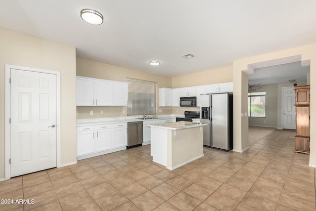 kitchen with sink, black appliances, light tile patterned floors, white cabinets, and a kitchen island