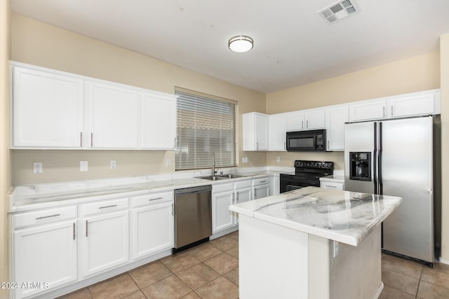 kitchen featuring light stone countertops, white cabinetry, a center island, sink, and black appliances