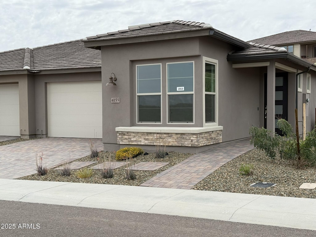 4155 Desert Moon Dr, Wickenburg, AZ 85390 - view of side of property with an attached garage, a tile roof, decorative driveway, stucco siding, and stone siding
